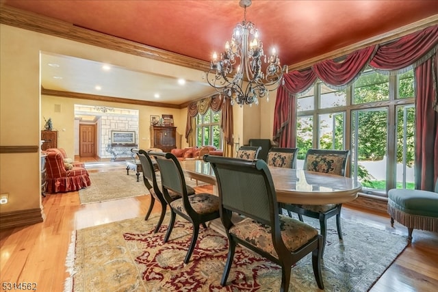 dining room with a notable chandelier, light hardwood / wood-style floors, plenty of natural light, and ornamental molding