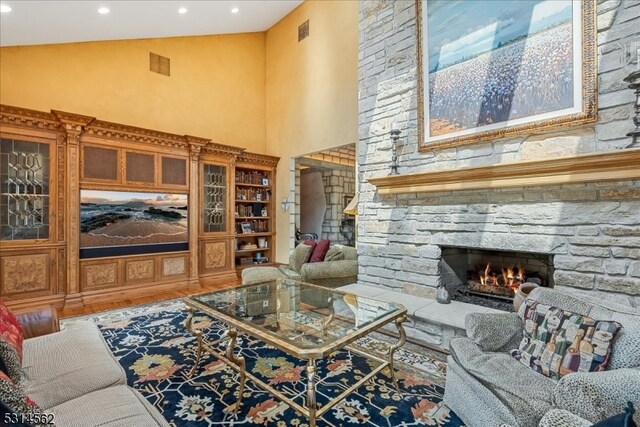 living room featuring a fireplace, hardwood / wood-style floors, and high vaulted ceiling