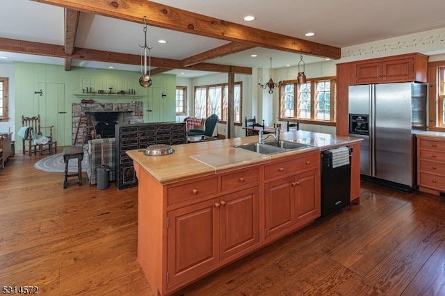 kitchen with black dishwasher, stainless steel fridge with ice dispenser, pendant lighting, and a center island with sink