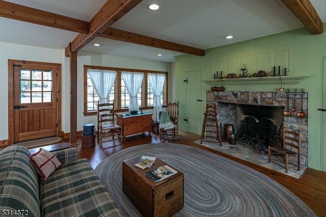 living room with a stone fireplace, hardwood / wood-style flooring, and beamed ceiling