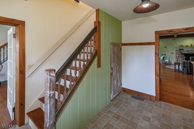 stairway with wooden walls, a fireplace, and hardwood / wood-style floors