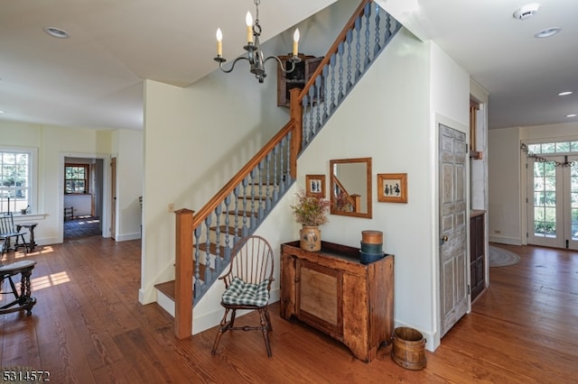 stairway with a chandelier, plenty of natural light, and hardwood / wood-style floors