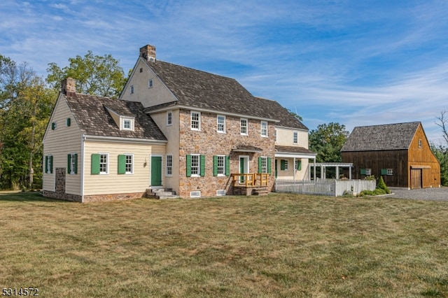 back of property with a yard and an outbuilding