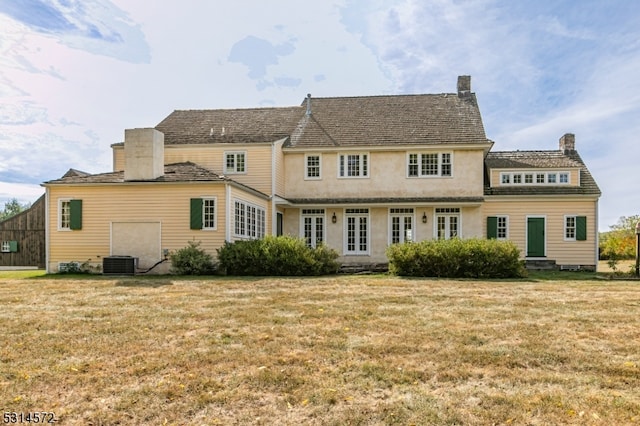 rear view of house featuring central AC and a yard