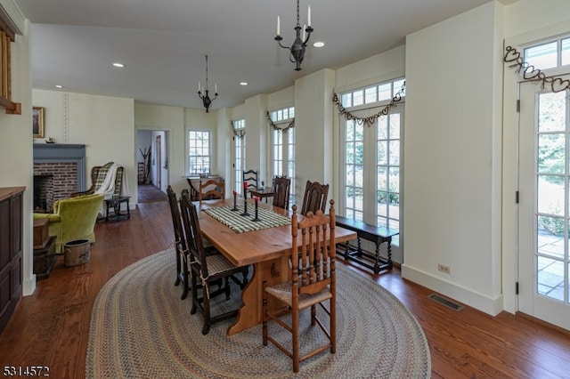 dining space featuring a fireplace, dark hardwood / wood-style floors, and an inviting chandelier