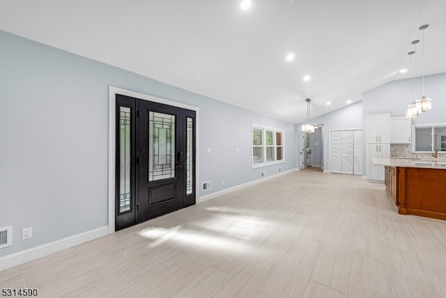 foyer entrance with vaulted ceiling and an inviting chandelier