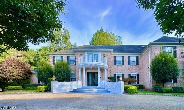 colonial-style house featuring french doors and a balcony