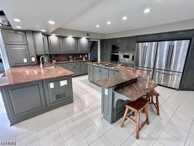 kitchen with gray cabinetry, a spacious island, sink, and dark stone counters