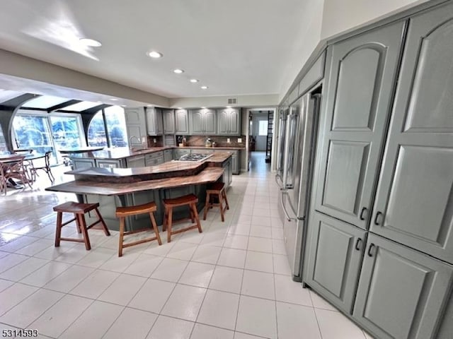 kitchen with gray cabinetry, sink, light tile patterned floors, and stainless steel appliances