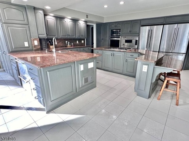 kitchen with stone counters, a center island, sink, stainless steel appliances, and tasteful backsplash