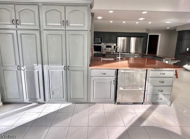 kitchen featuring stone countertops, light tile patterned flooring, sink, and stainless steel appliances