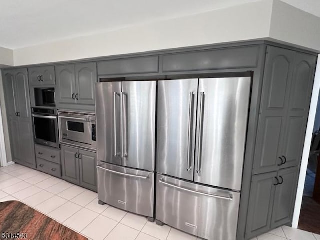 kitchen with gray cabinets, light tile patterned floors, and appliances with stainless steel finishes