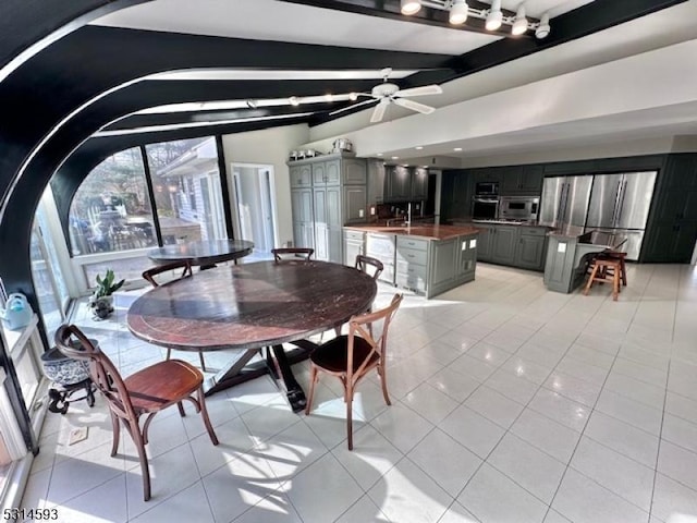 dining room featuring ceiling fan, light tile patterned flooring, and lofted ceiling with beams