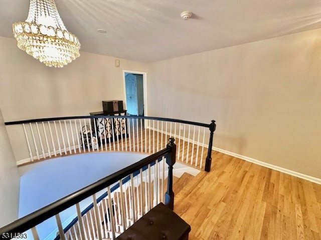 staircase with hardwood / wood-style floors and a chandelier