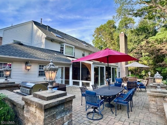 rear view of house with an outdoor bar, an outdoor kitchen, a patio, and a sunroom