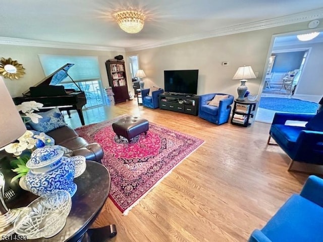 living room with wood-type flooring, crown molding, and an inviting chandelier