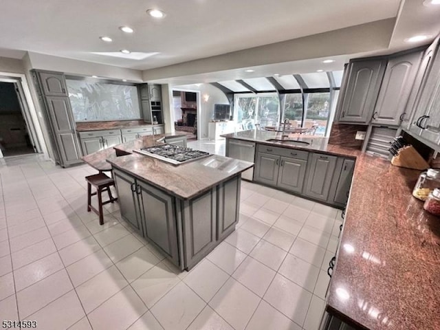 kitchen featuring gray cabinetry, a center island, sink, light tile patterned floors, and appliances with stainless steel finishes