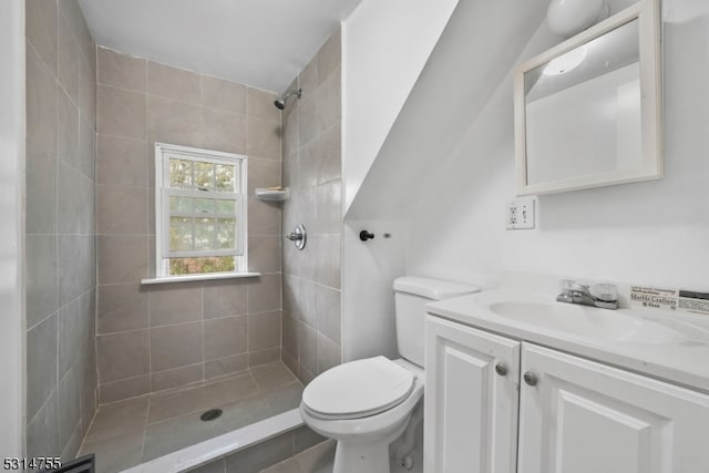 bathroom with tile patterned floors, tiled shower, vanity, and toilet