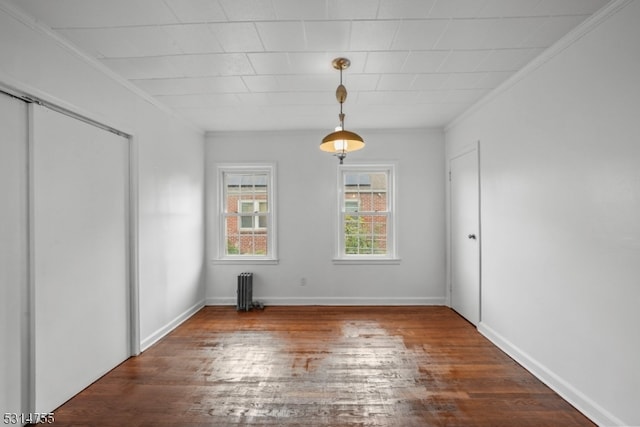 spare room featuring radiator, crown molding, and dark hardwood / wood-style flooring