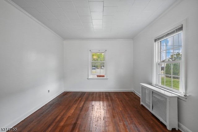 empty room with radiator, ornamental molding, and dark wood-type flooring