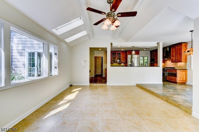 unfurnished living room with vaulted ceiling with skylight, ceiling fan, and light tile patterned floors