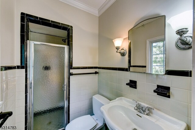 bathroom featuring tile walls, sink, a shower with shower door, and toilet