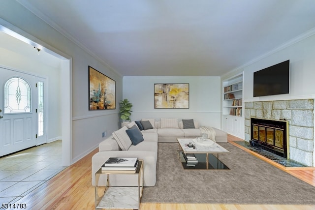 living room with light hardwood / wood-style floors, crown molding, a fireplace, and built in features