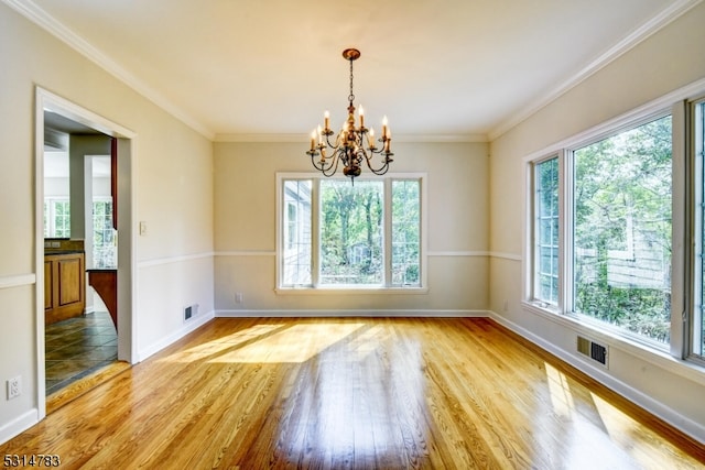 spare room with ornamental molding, a chandelier, light hardwood / wood-style floors, and a healthy amount of sunlight