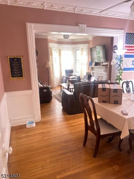 dining space featuring wood-type flooring and crown molding