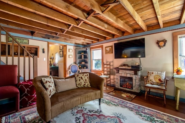 living room with a stone fireplace and beamed ceiling