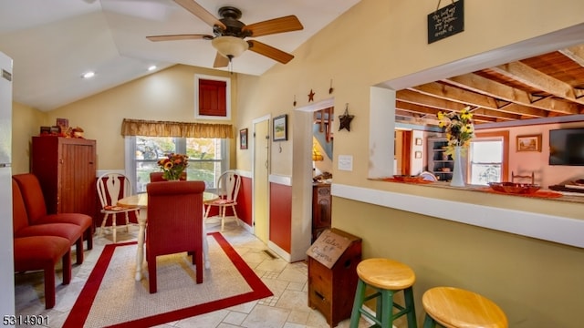 dining room featuring vaulted ceiling with beams, ceiling fan, and plenty of natural light