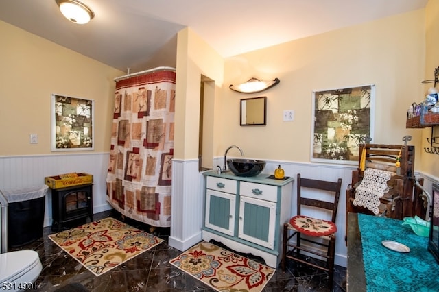 interior space with toilet, a shower with shower curtain, and a wood stove