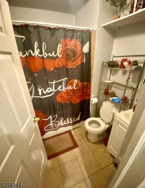 bathroom featuring vanity, toilet, a shower with shower curtain, and tile patterned floors