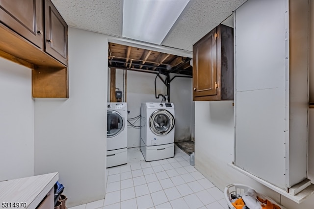 washroom with cabinets, light tile patterned floors, and washer and clothes dryer