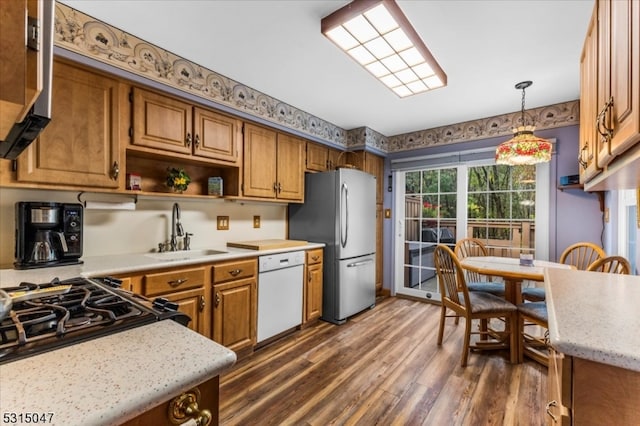 kitchen with stainless steel appliances, hanging light fixtures, sink, and dark hardwood / wood-style flooring