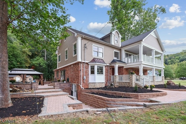 rear view of property featuring a balcony and a gazebo