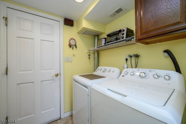 clothes washing area featuring washing machine and clothes dryer and cabinets