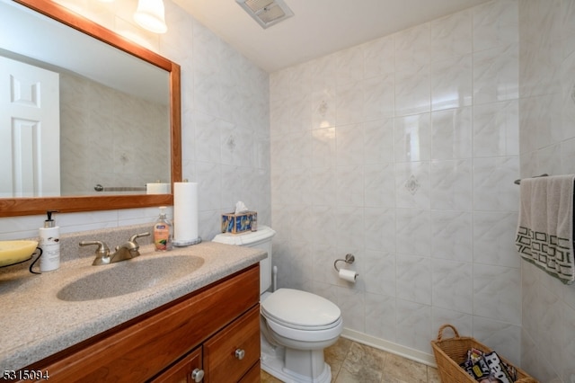 bathroom with vanity, tile walls, tile patterned flooring, and toilet