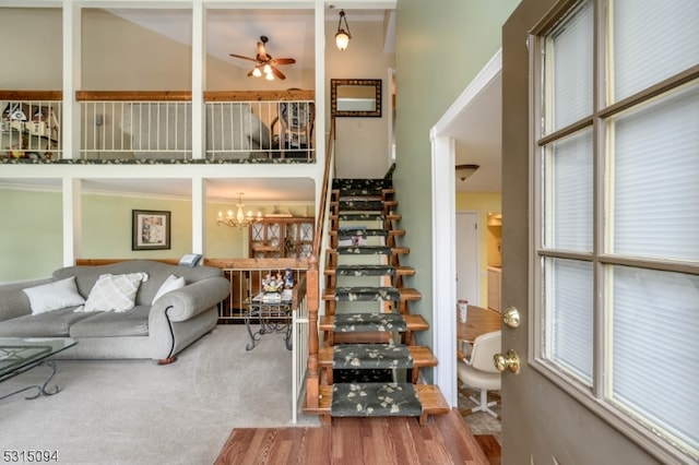 living room featuring ceiling fan with notable chandelier, hardwood / wood-style floors, and high vaulted ceiling