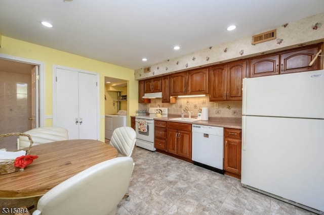 kitchen featuring backsplash, white appliances, sink, and independent washer and dryer