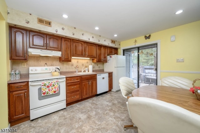 kitchen featuring decorative backsplash, white appliances, and sink