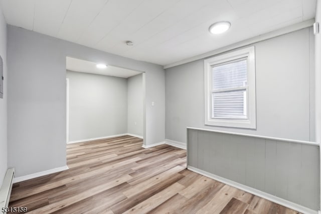 empty room with light hardwood / wood-style floors and a baseboard heating unit