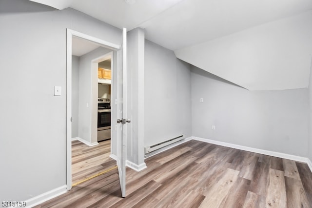 additional living space featuring a baseboard heating unit and hardwood / wood-style flooring