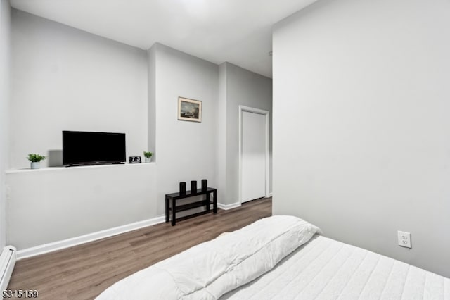 bedroom with a baseboard heating unit and dark wood-type flooring