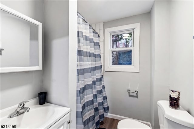 bathroom with walk in shower, vanity, toilet, and wood-type flooring