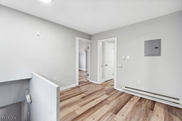 unfurnished room with a baseboard heating unit, electric panel, and hardwood / wood-style floors