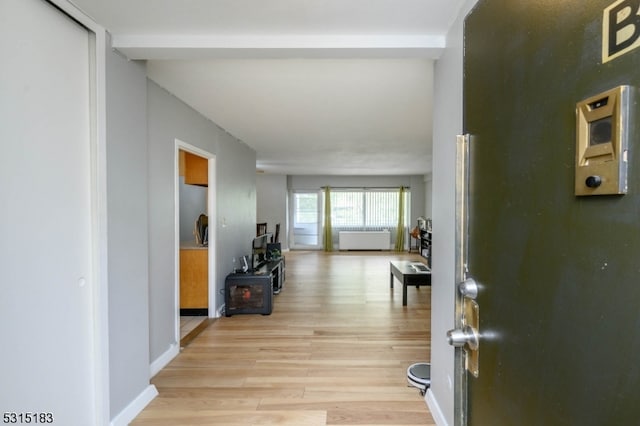 corridor with light wood-type flooring and radiator