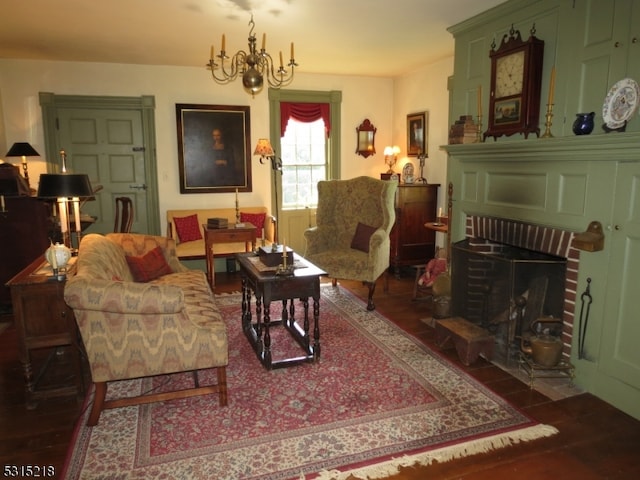 living room with an inviting chandelier, a fireplace, and dark wood-type flooring