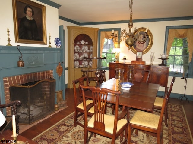 dining room with ornamental molding, a notable chandelier, a fireplace, and dark hardwood / wood-style flooring