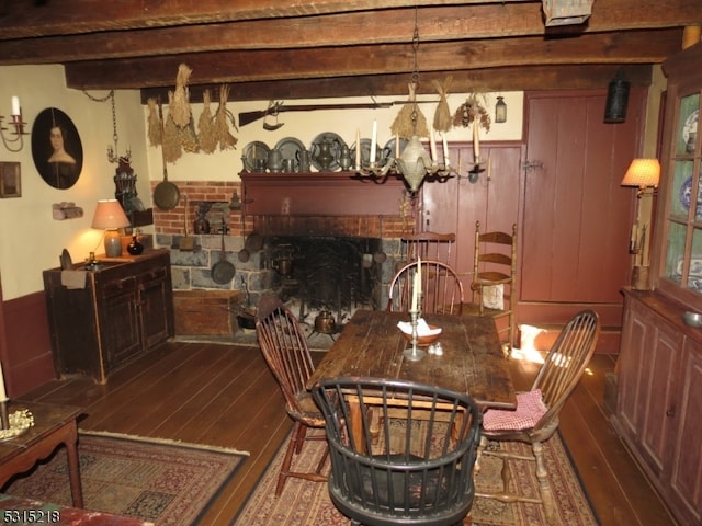 dining area with a brick fireplace, beamed ceiling, and hardwood / wood-style floors